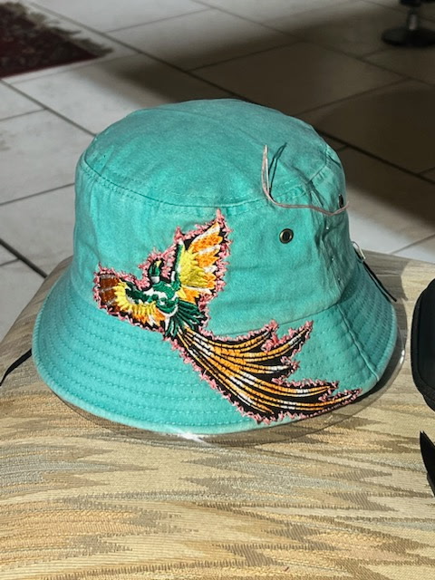Teal bucket hat hand-embroidered with a red and orange bird in flight